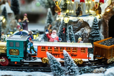 Model train set decorated for Christmas with fake snow and lights with Santa Claus on top of the train waving