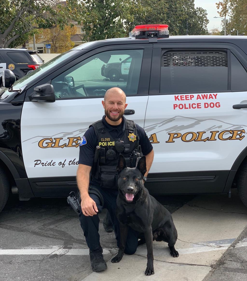 Officer Cloud poses in front of a police car with his K9 partner Sam